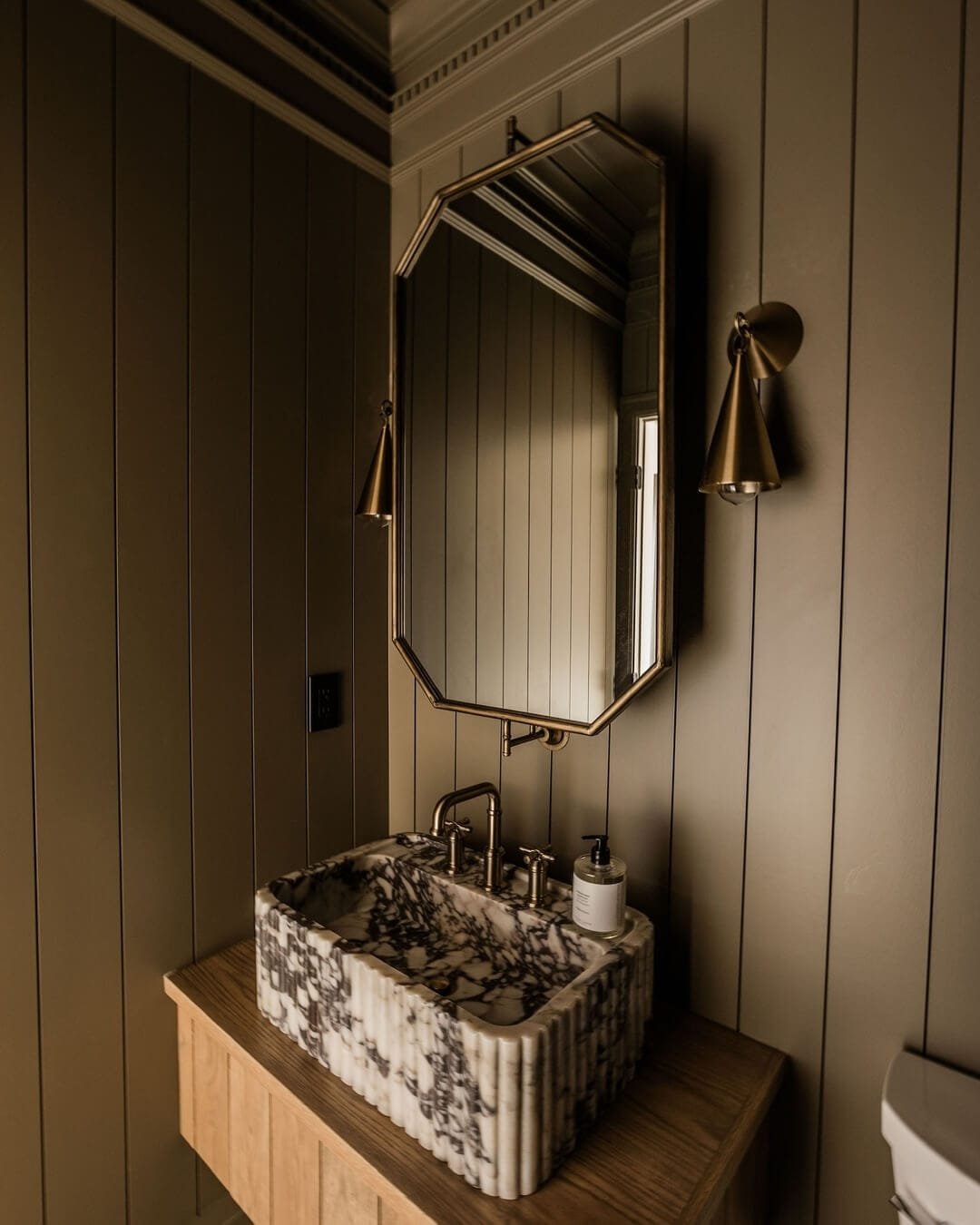 Vertical paneling and marble sinks enhance bathroom elegance